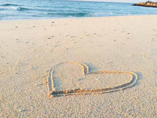 Bilde av et hjerte tegnet i sanden på en strand